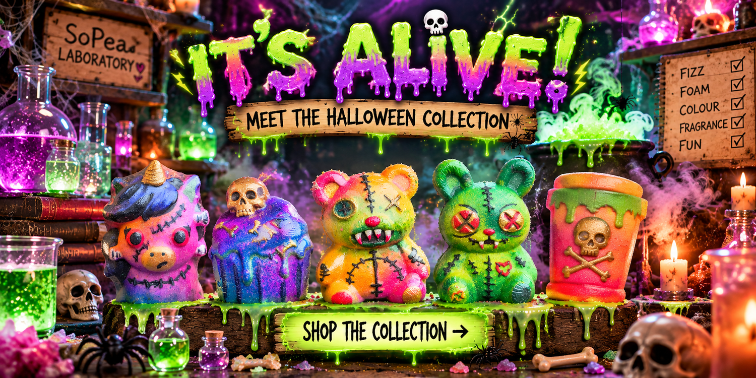 A Halloween-themed promotional display featuring colourful stitched monster and zombie figures, a green cup with a skull graphic, candles, jars of green liquid, and spooky signage reading 'IT'S ALIVE! MEET THE HALLOWEEN COLLECTION' and 'SHOP THE COLLECTION'. Colourful Halloween bath bombs in the SoPea laboratory